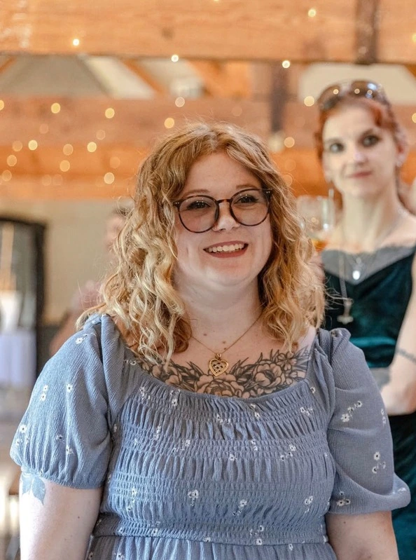 A picture of Bea, the person behind wander without limits travel. She has ginger hair, round glasses and is wearing a blue dress